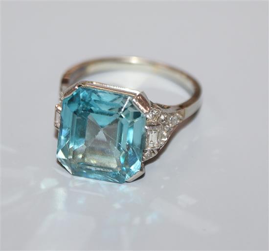 A white metal and blue zircon ring with diamond set shoulders (stone chip), size K.